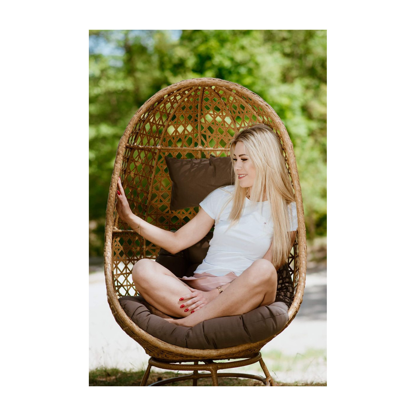 Kobieta siedząca w krześle obrotowym z technorattanu w naturalnym środowisku