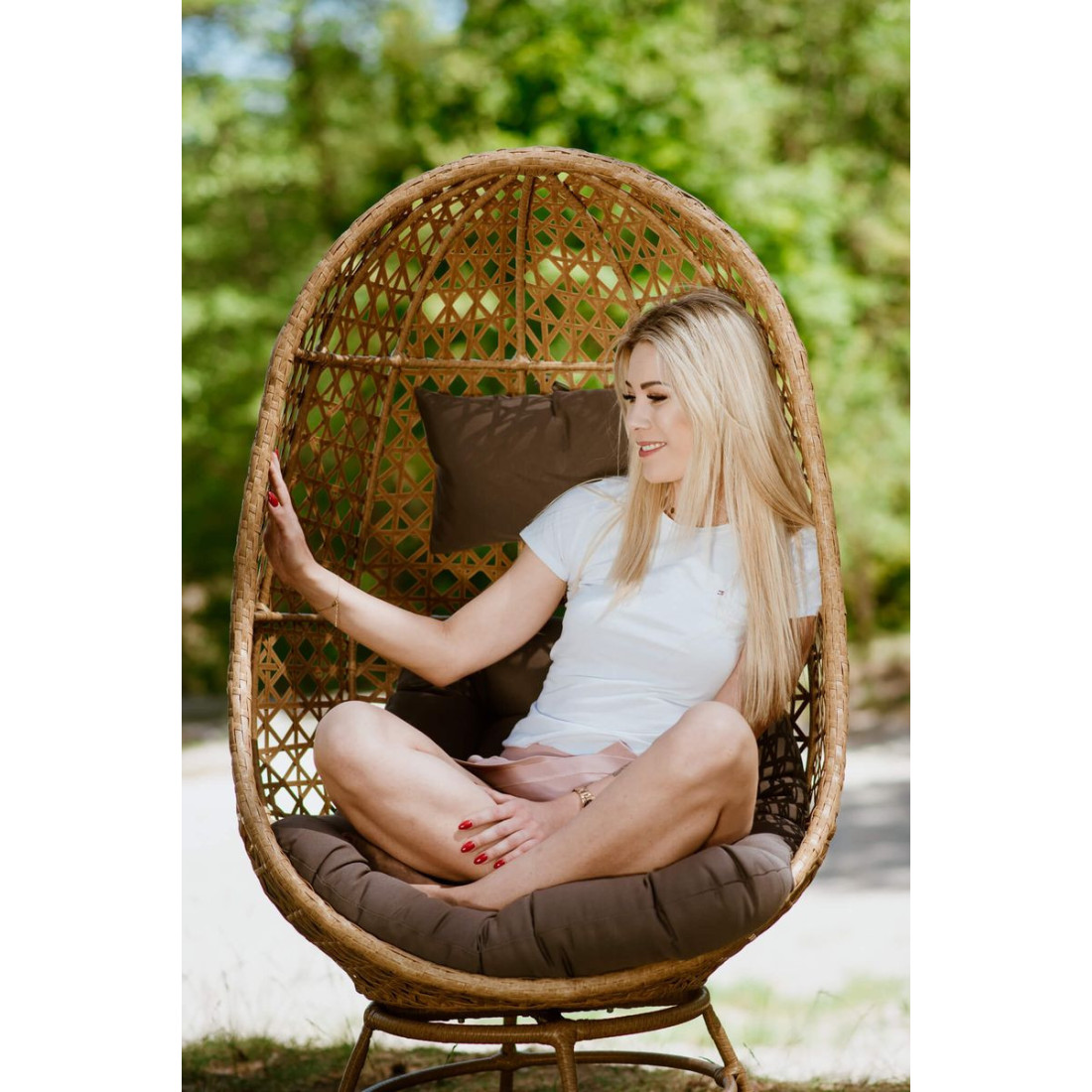 Kobieta siedząca w krześle obrotowym z technorattanu w naturalnym środowisku