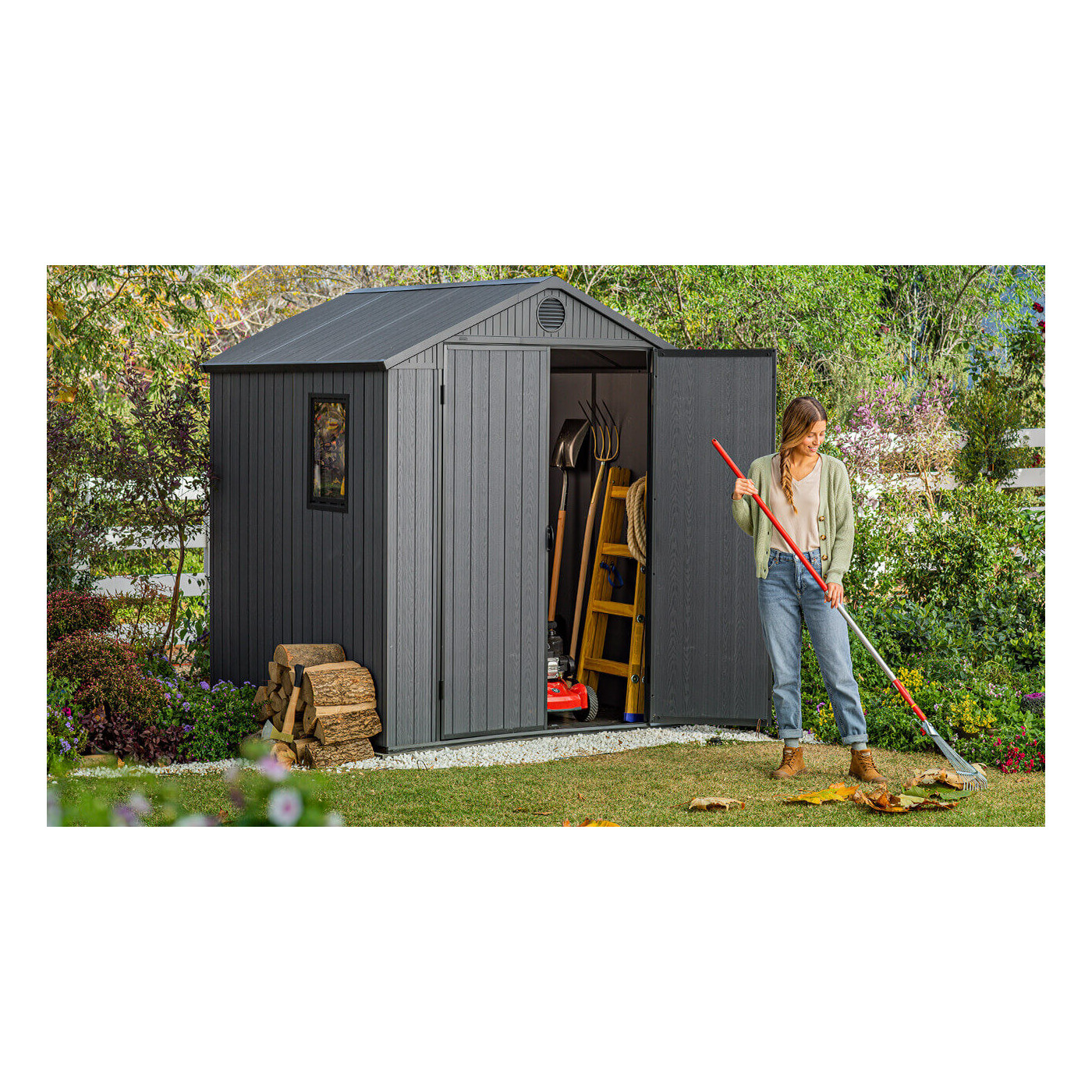 Widok pracującej kobiety w ogrodzie i umieszczonym za nią domku Darwin na narzędzia