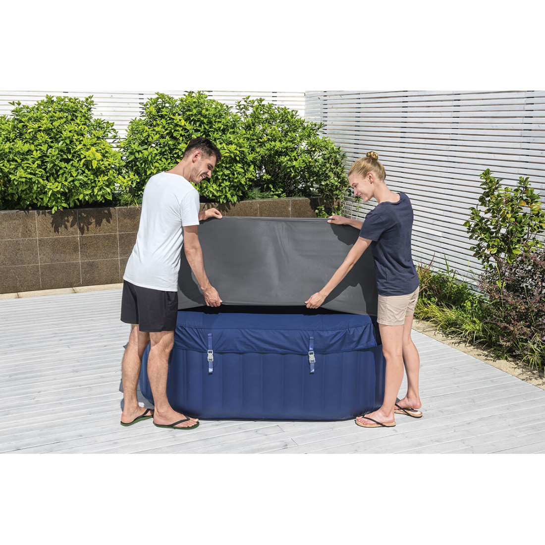 Widok na kobietę i mężczyznę, którzy nakładają pokrywę termiczną na jacuzzi