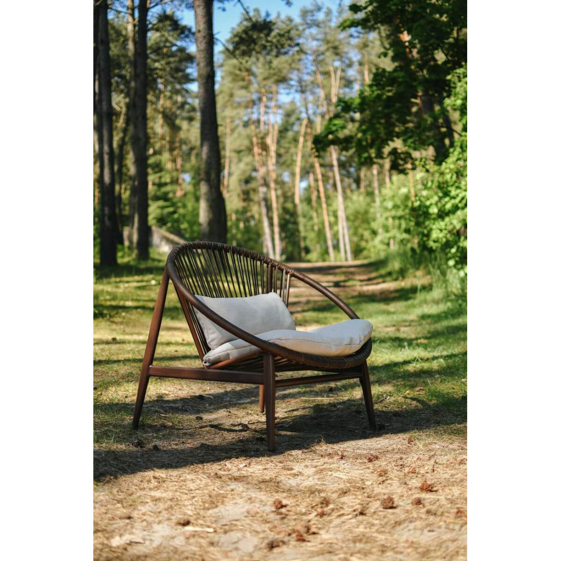 Kobieta siedząca na fotelu ogrodowym w naturalnym środowisku