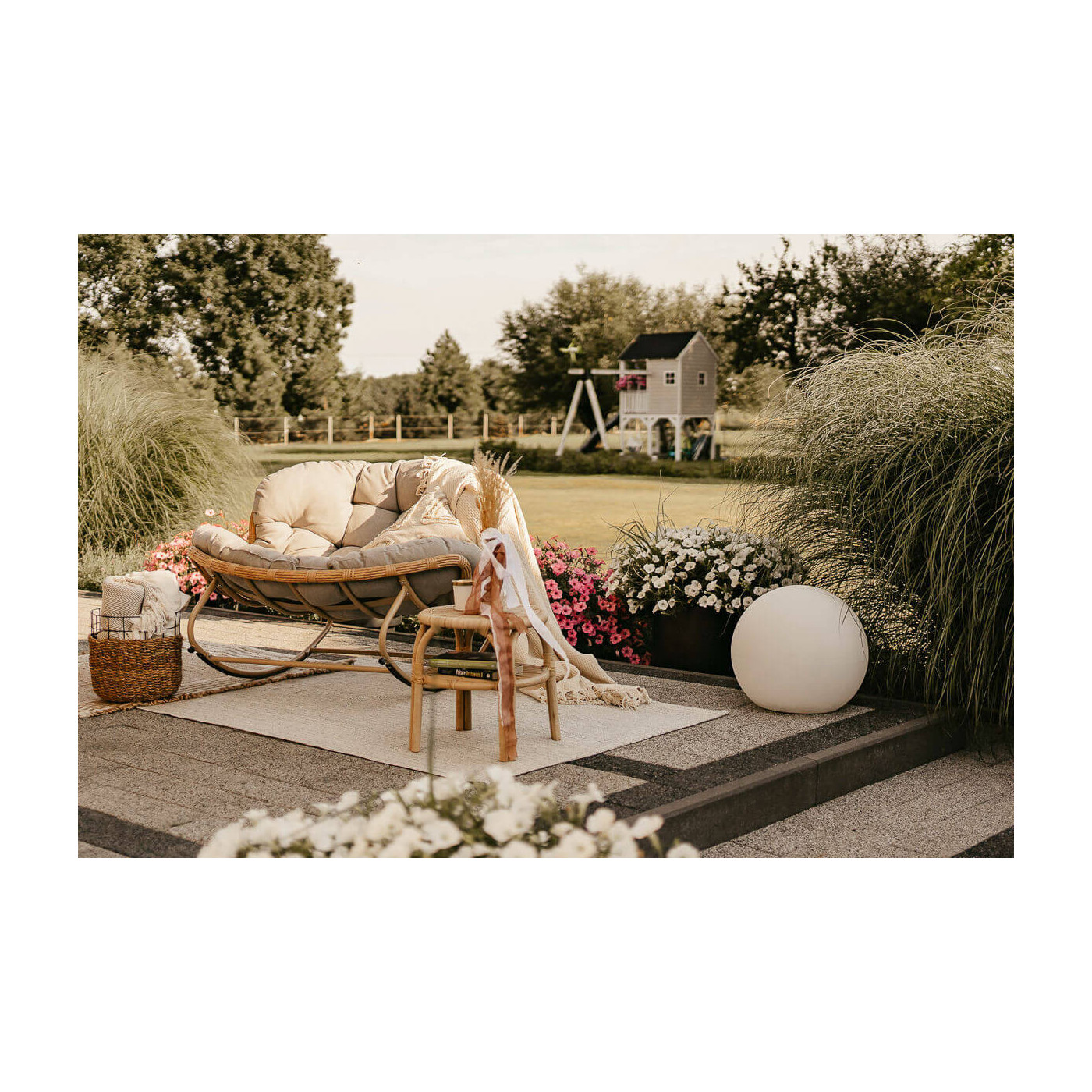 Wiosenna aranżacja fotela, a w tle drewniany domek dla dzieci