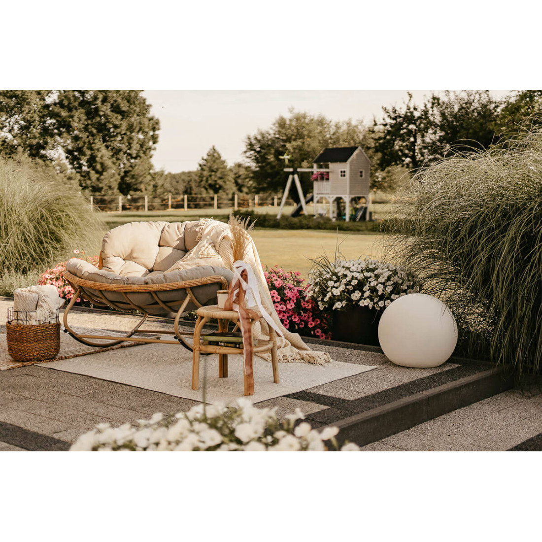 Wiosenna aranżacja fotela, a w tle drewniany domek dla dzieci