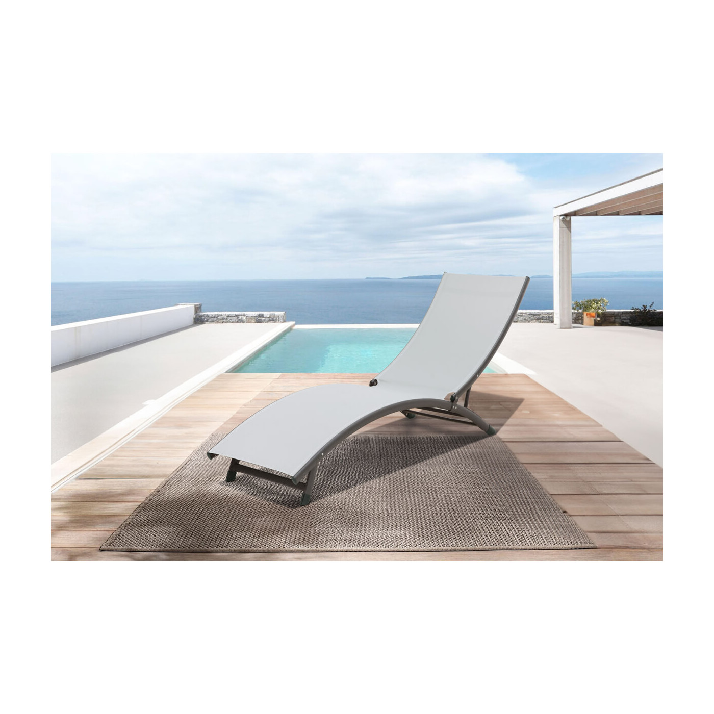 leżak z aluminium star w kolorze jasno szarym na eleganckim tarasie za leżakiem widoczny basen w tle ocean