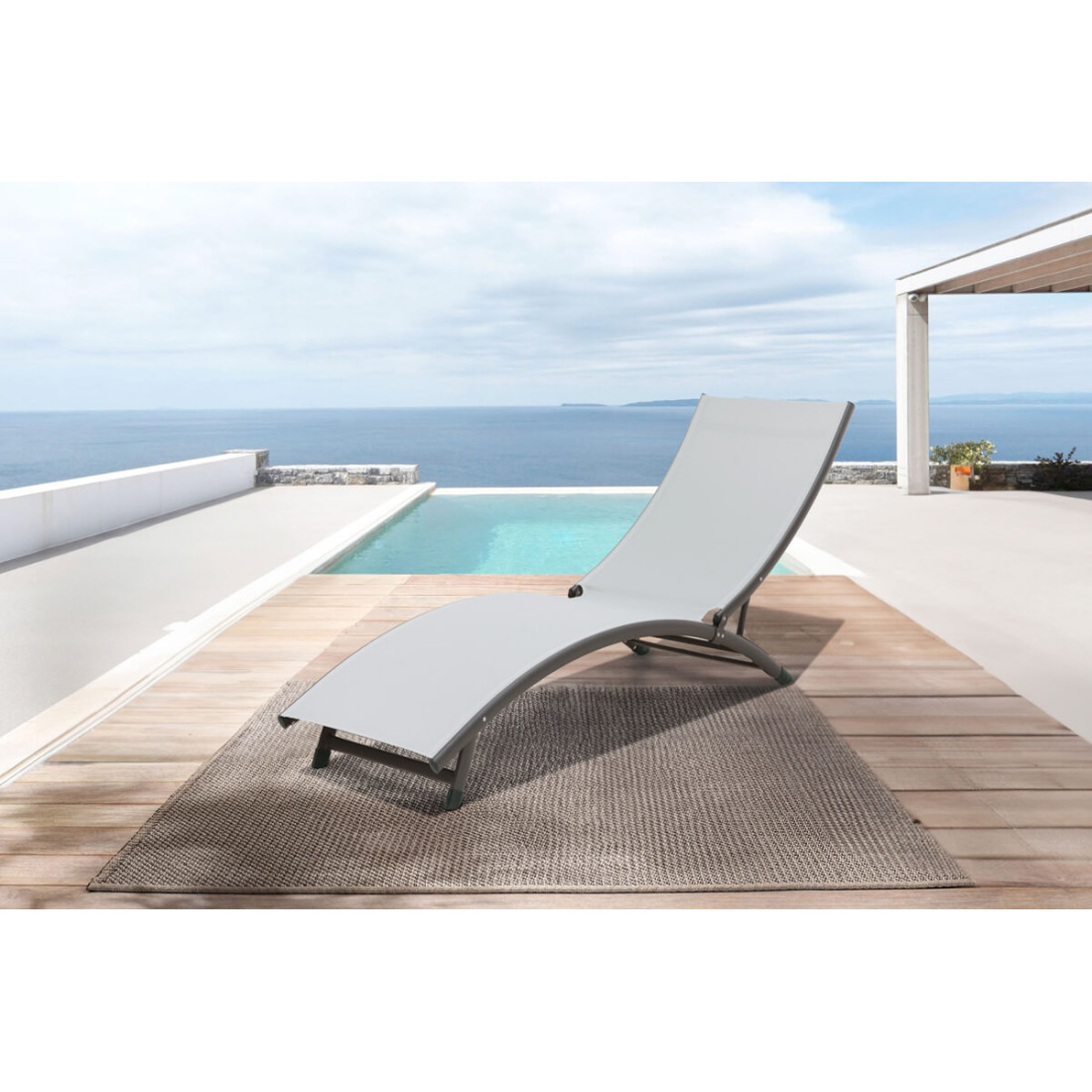 leżak z aluminium star w kolorze jasno szarym na eleganckim tarasie za leżakiem widoczny basen w tle ocean