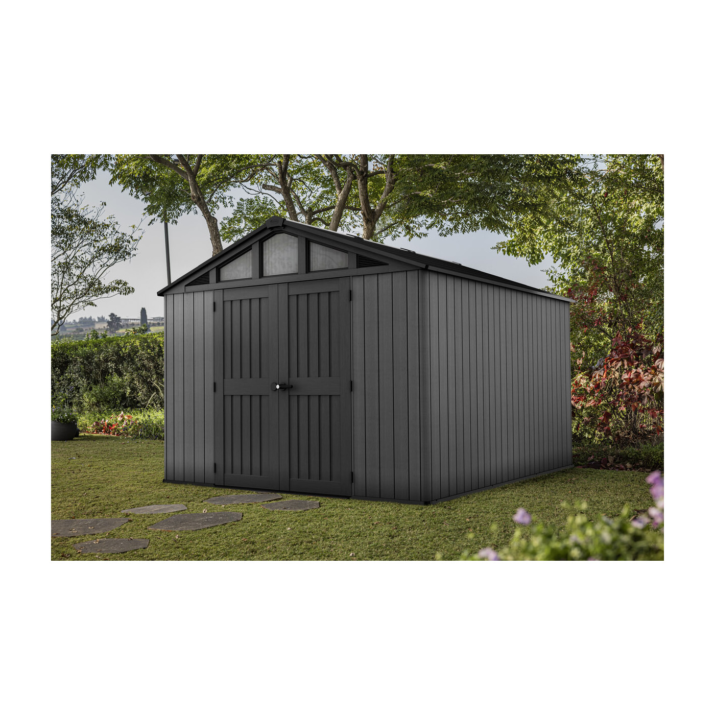 Domek na narzędzia w przydomowym ogródku na zielonej trawie pod koroną drzew