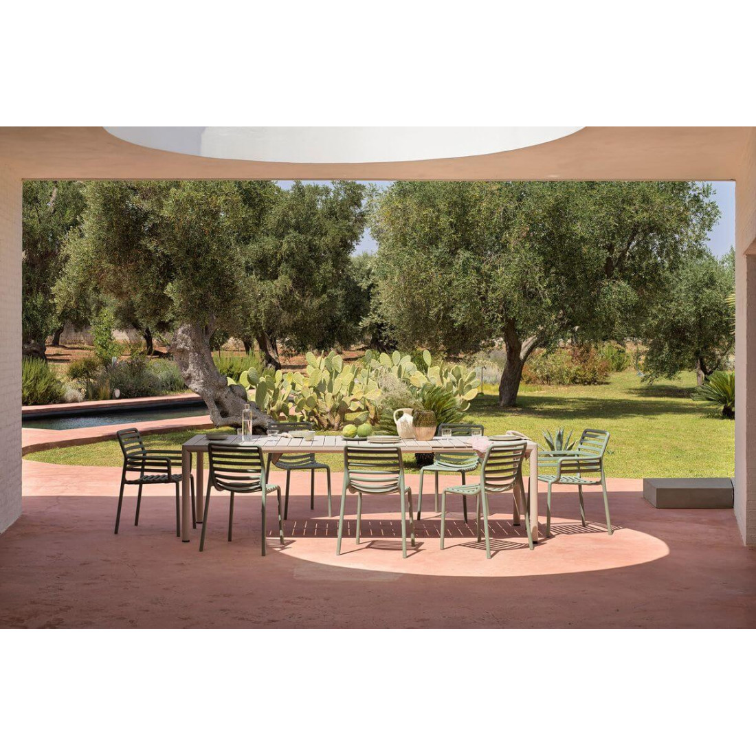 Rozłożony stół TEVERE 210 Corda na przestronnym tarasie, z widokiem na drzewa i ogród