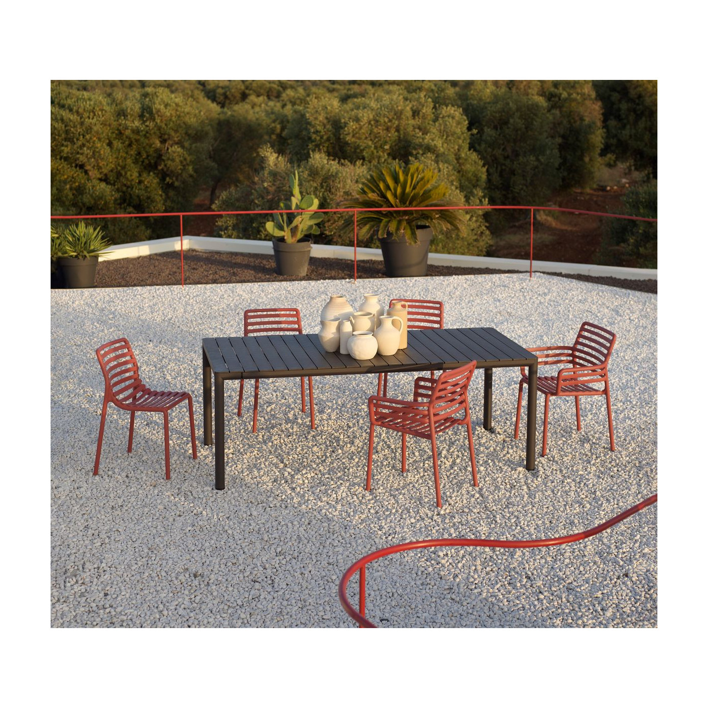 Stół ogrodowy Tevere 210 w kolorze antracytowym z czerwonymi krzesłami Nardi na tarasie